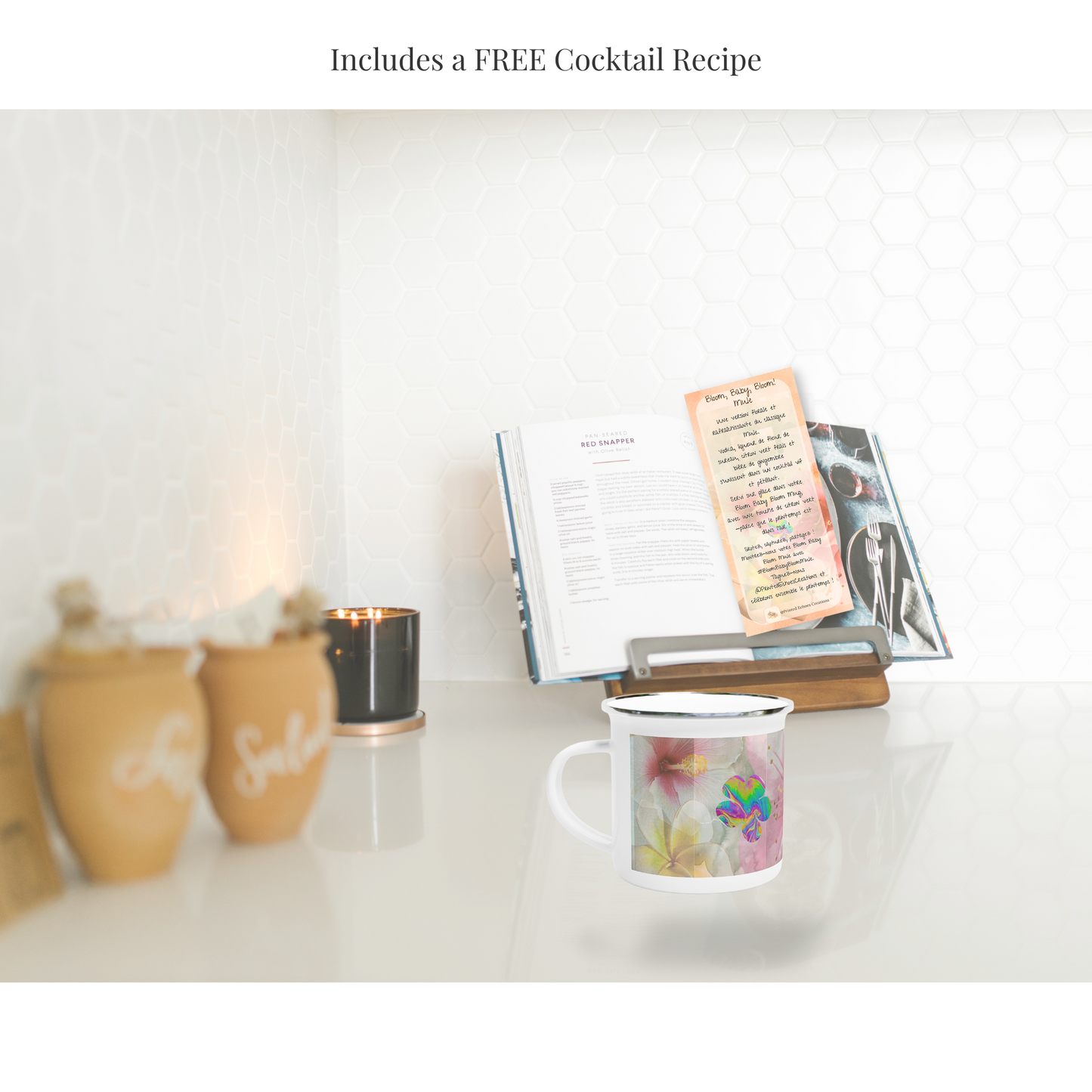 12oz Bloom, Baby, Bloom! enamel mug with silver rim, placed in a cozy kitchen setting. The mug sits next to an open cookbook, with a recipe card on display, teasing an exclusive free cocktail recipe included with purchase.