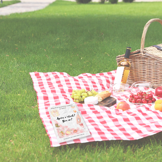 Apéro Invite card from Printed Echoes Creations resting on a red gingham picnic blanket with summer fruits, wine, and cheese, evoking a poetic apéro moment in the grass.