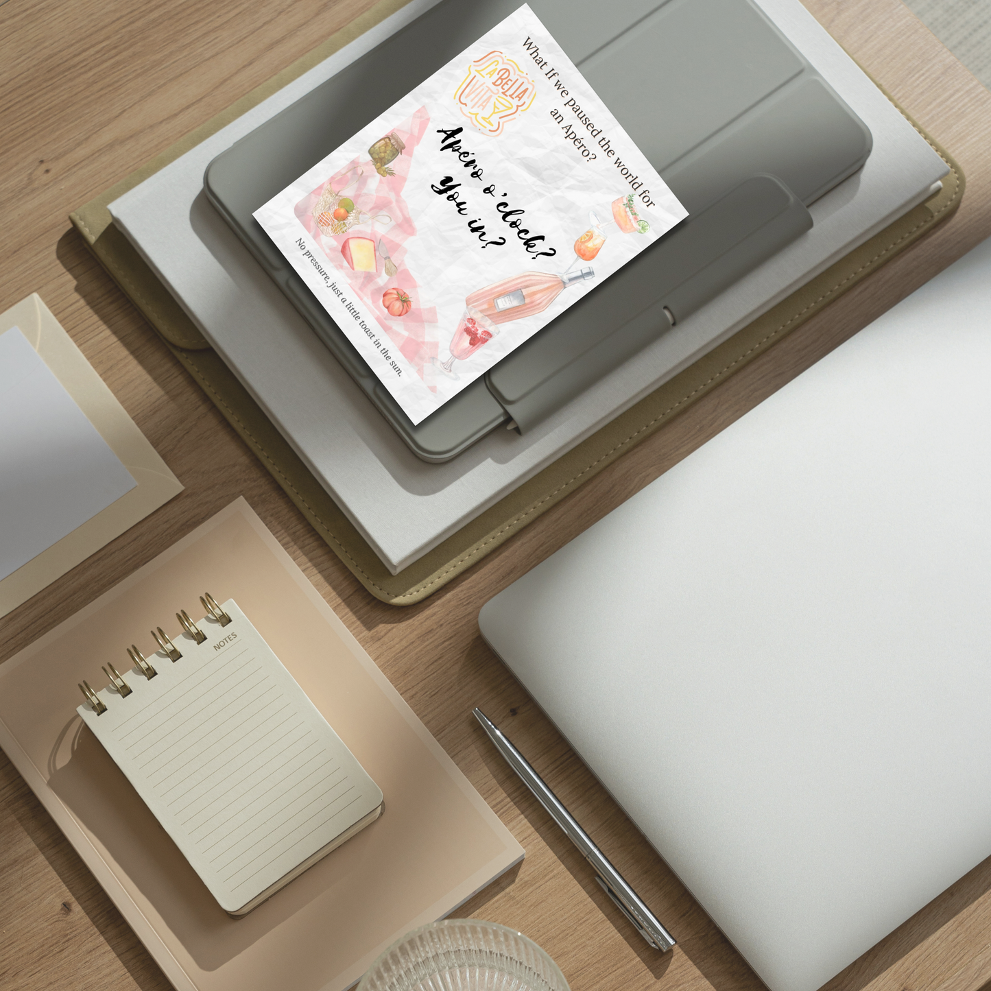 What-If Apéro Invite card displayed on a tidy desk with neutral stationery, showing the card’s flat format and poetic summer design by Printed Echoes Creations.