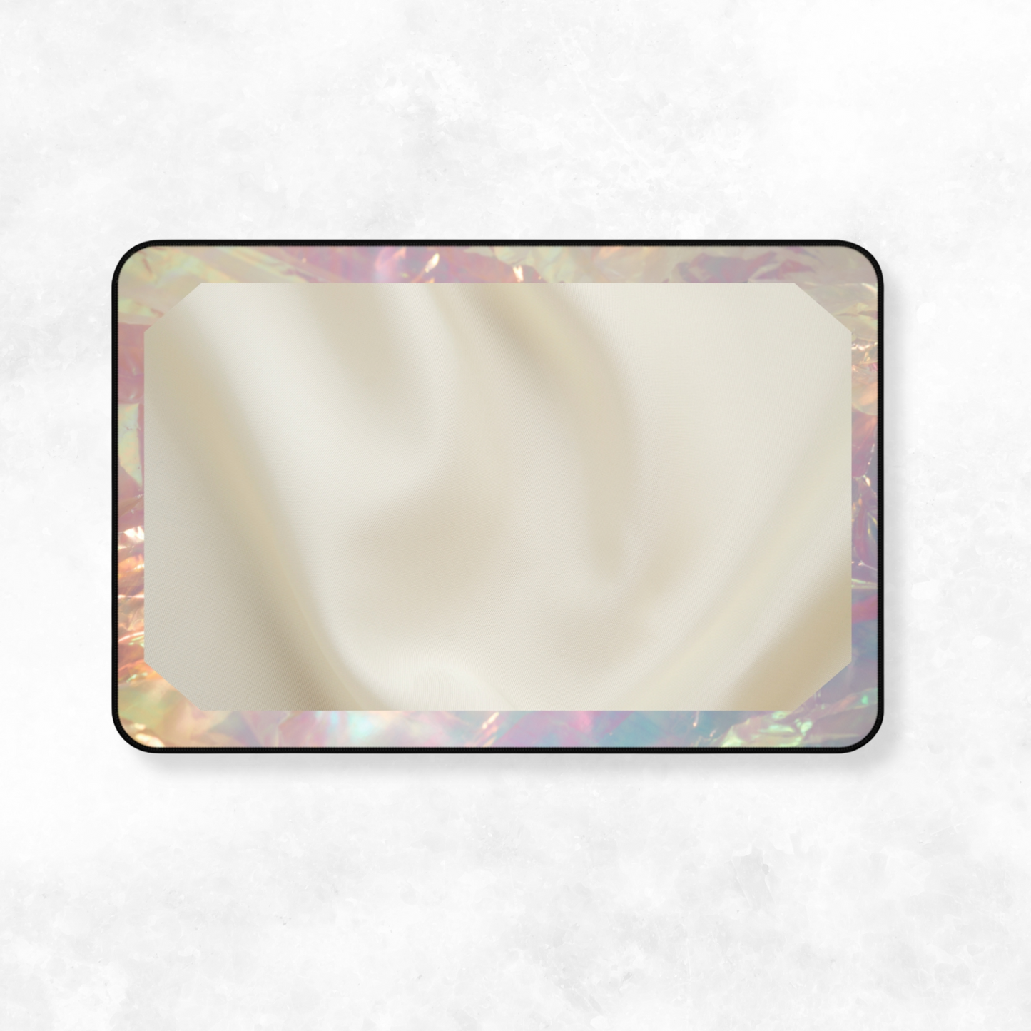 Soft-touch desk mat with iridescent frame and cream-toned fabric texture, laid flat against a white surface