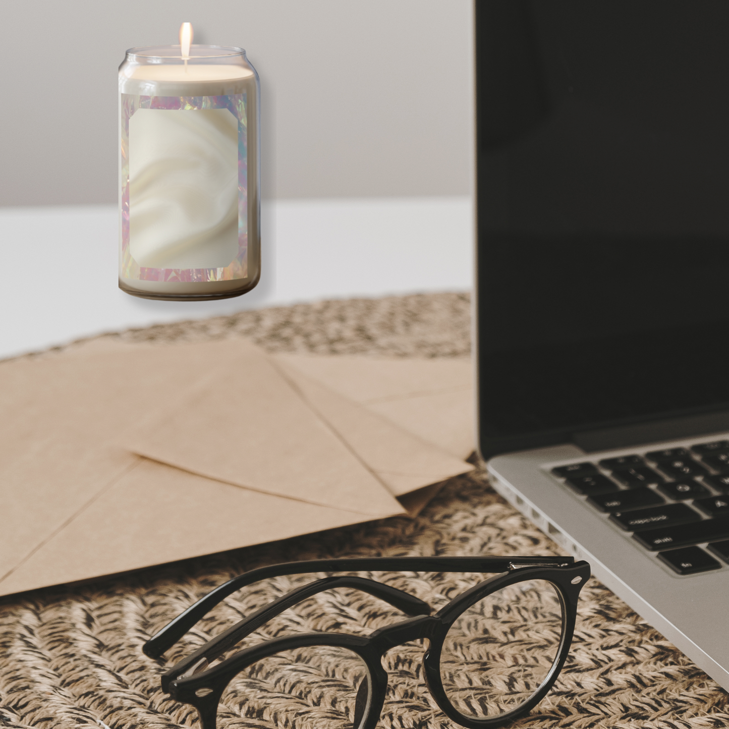 Return Glow candle styled next to glasses, kraft paper, and laptop on a woven surface with clean lighting