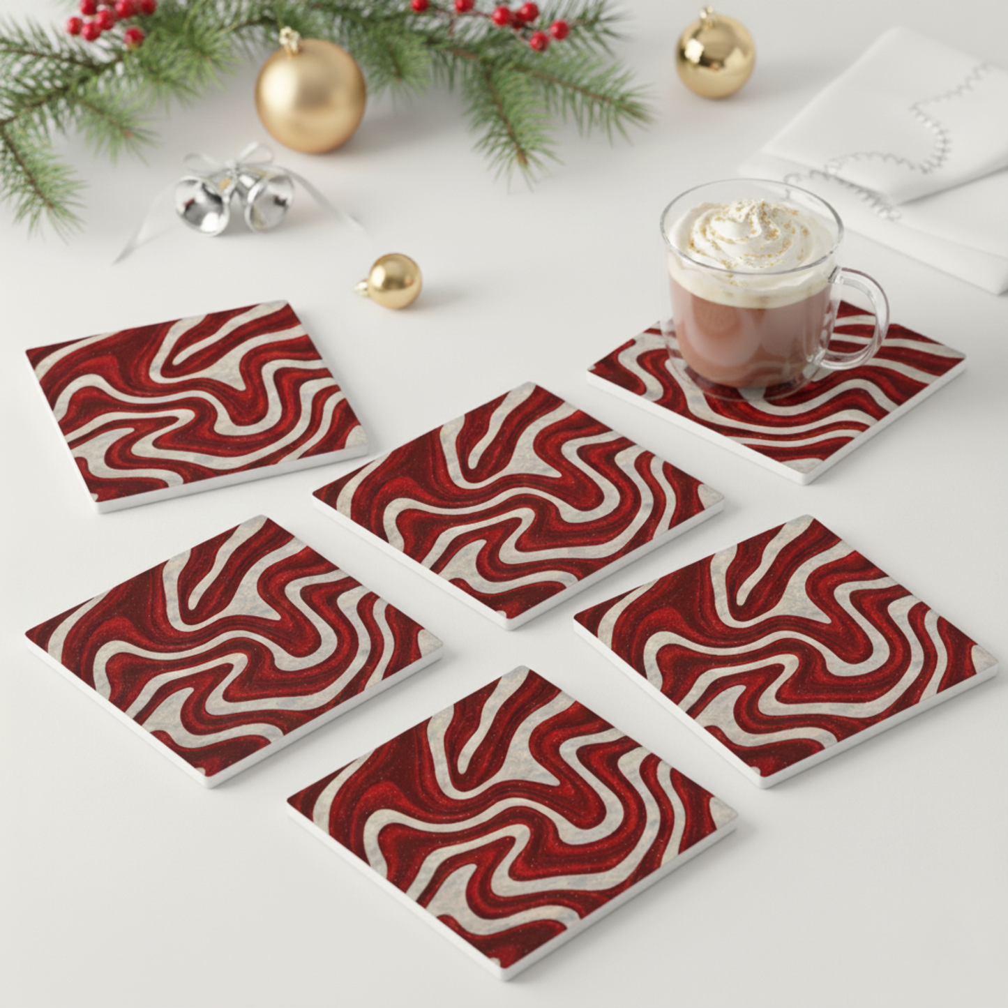 Set of six Candy Swirl ceramic coasters in bold red and white pattern, styled with hot chocolate and holiday décor — modern Christmas table accents and hostess gift from Printed Echoes Creations.
