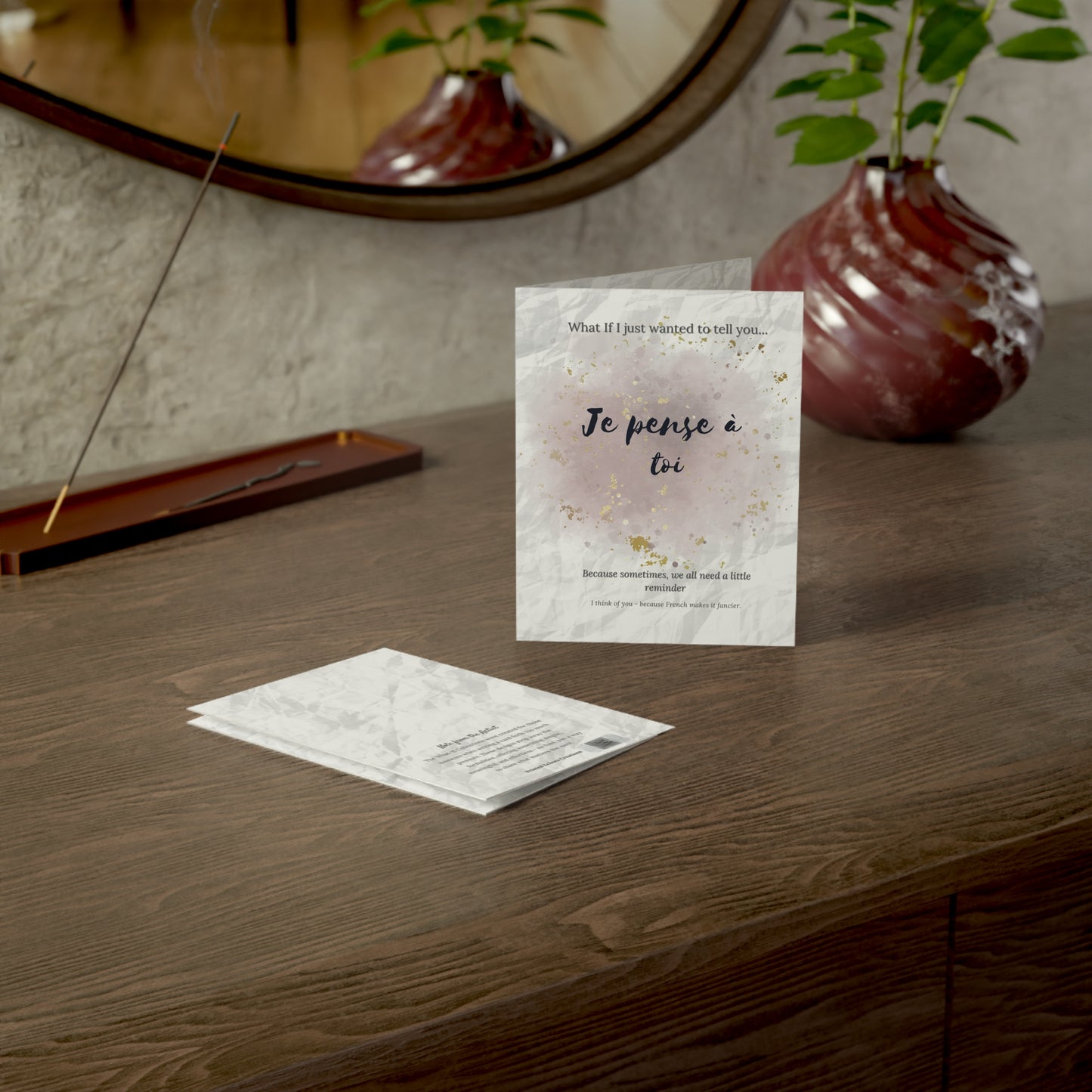 Je pense à toi card styled on a wooden desk beside a mirror and a ceramic vase, part of the What-If Collection by Printed Echoes Creations.