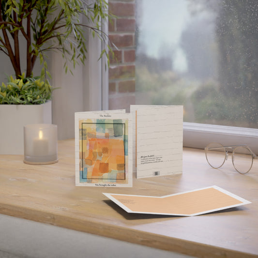 A minimalist art greeting card titled “The Builder,” resting on a wooden desk in natural light. The card features an abstract watercolor design in orange and golden tones, set against a white brick background. An original Father’s Day card for dads, stepdads, or chosen family who bring warmth into everyday life.