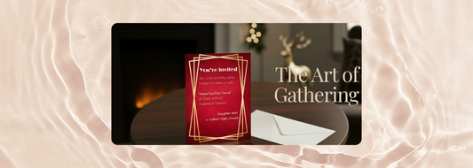 Holiday invitation card with red and gold Art Deco design on table near fireplace — banner for Printed Echoes Creations blog article The Art of Gathering, celebrating intentional and personalized holiday stationery.