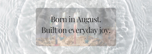 Birthday candles glowing softly under water-like light, paired with poetic text “Born in August. Built on everyday joy.” A dreamy, nostalgic visual reflecting summer birthdays and quiet celebration.