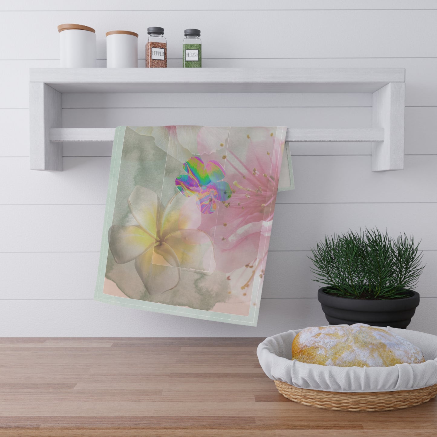 Bloom, Baby, Bloom! tea towel displayed on a white kitchen rack beside fresh bread and herbs, showcasing its artistic floral design in a cozy countertop setting.