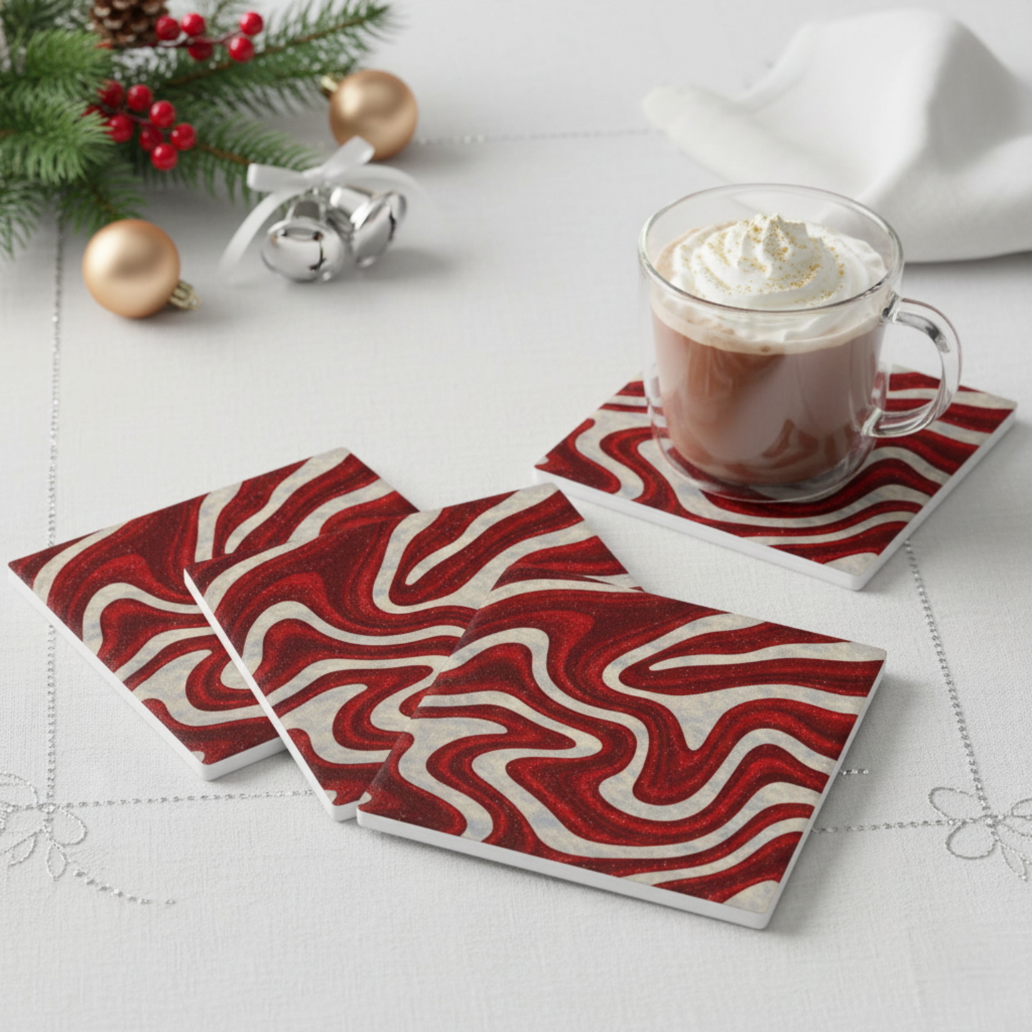 Set of four Candy Swirl ceramic coasters in red and white abstract design, styled with hot chocolate and festive holiday table décor — modern Christmas host gift from Printed Echoes Creations.