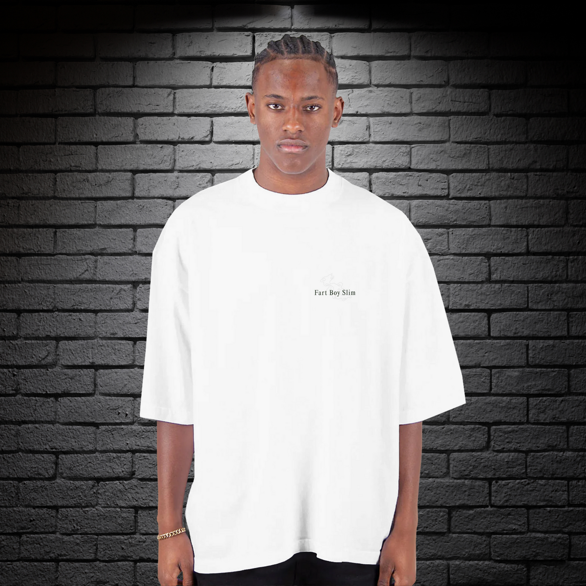 Front view of white oversized Fart Boy Slim t-shirt with subtle graphic, styled against a black brick wall.