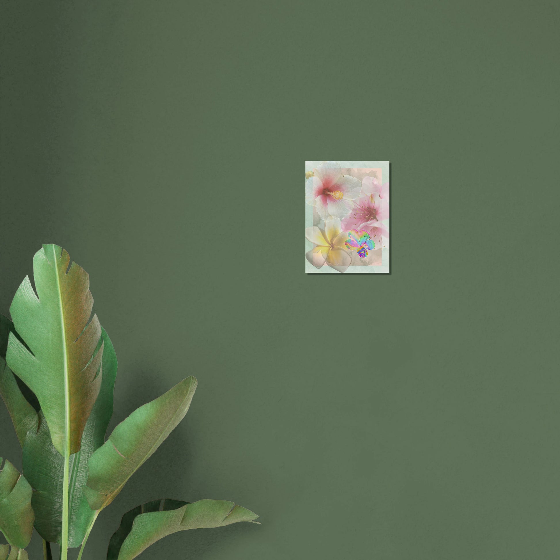 Small surreal floral art print displayed on a green wall with tropical leaves, showcasing dreamy hibiscus and iridescent accents.
