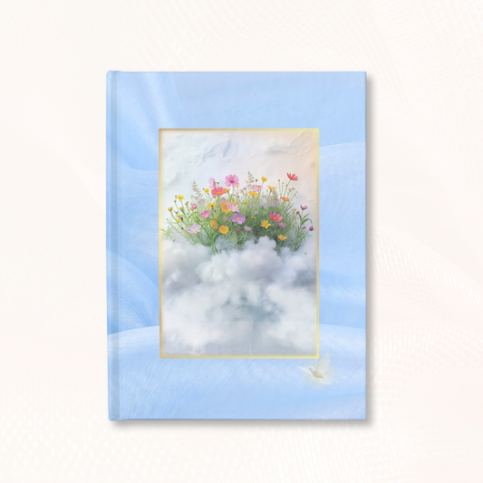 Hardcover Garden of Dreams journal with a soft blue wraparound cover, featuring fine art wildflowers floating on a cloud, photographed on a neutral textured background.