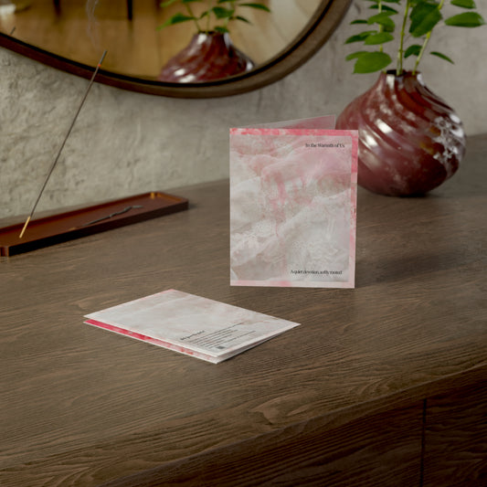 "In the Warmth of Us” wedding card displayed on a wooden desk with a soft candle, mirror, and ceramic vase in the background. A poetic and elegant wedding greeting card.