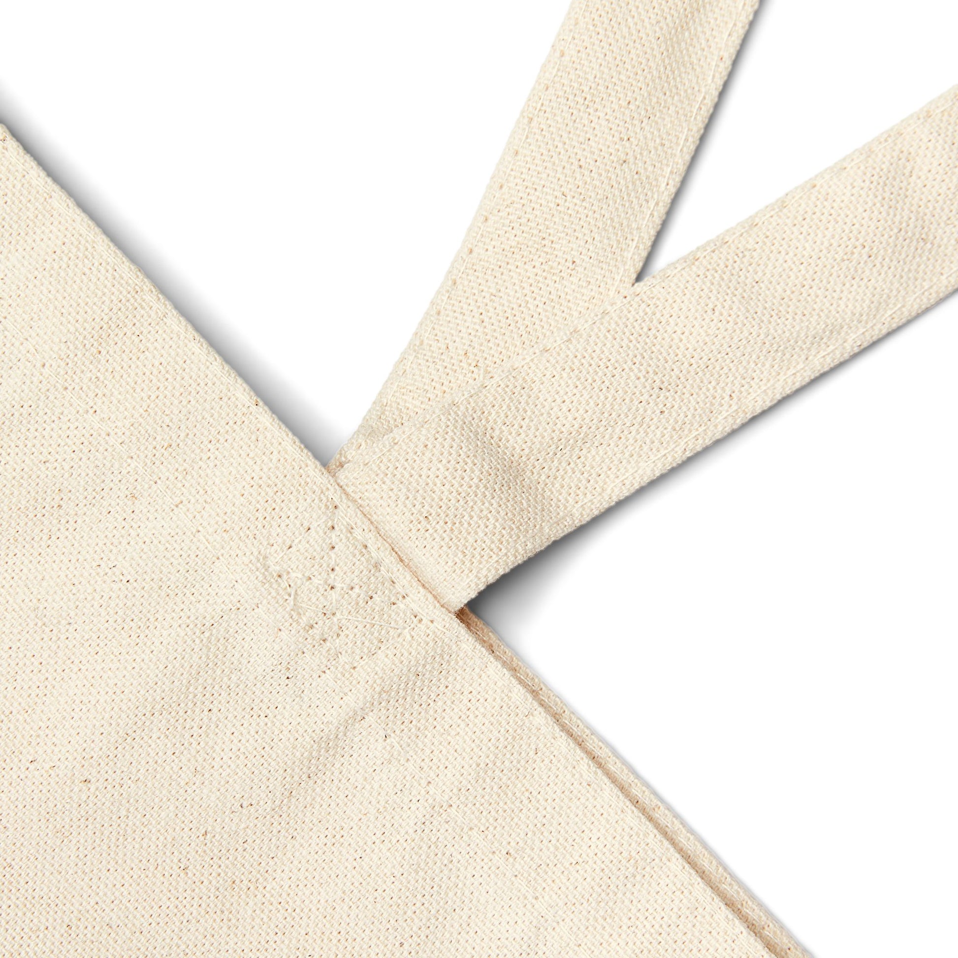 close-up of the cotton canvas tote bag stitching and reinforced handle construction, showing the natural fabric texture and durable craftsmanship